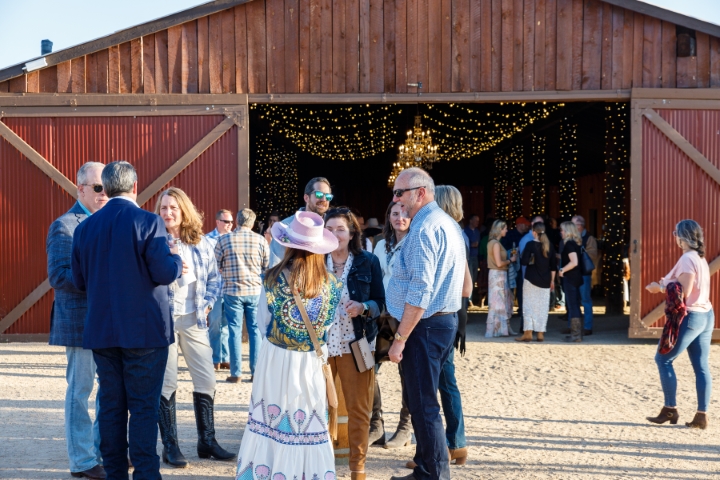 a group of people standing outside of a barn